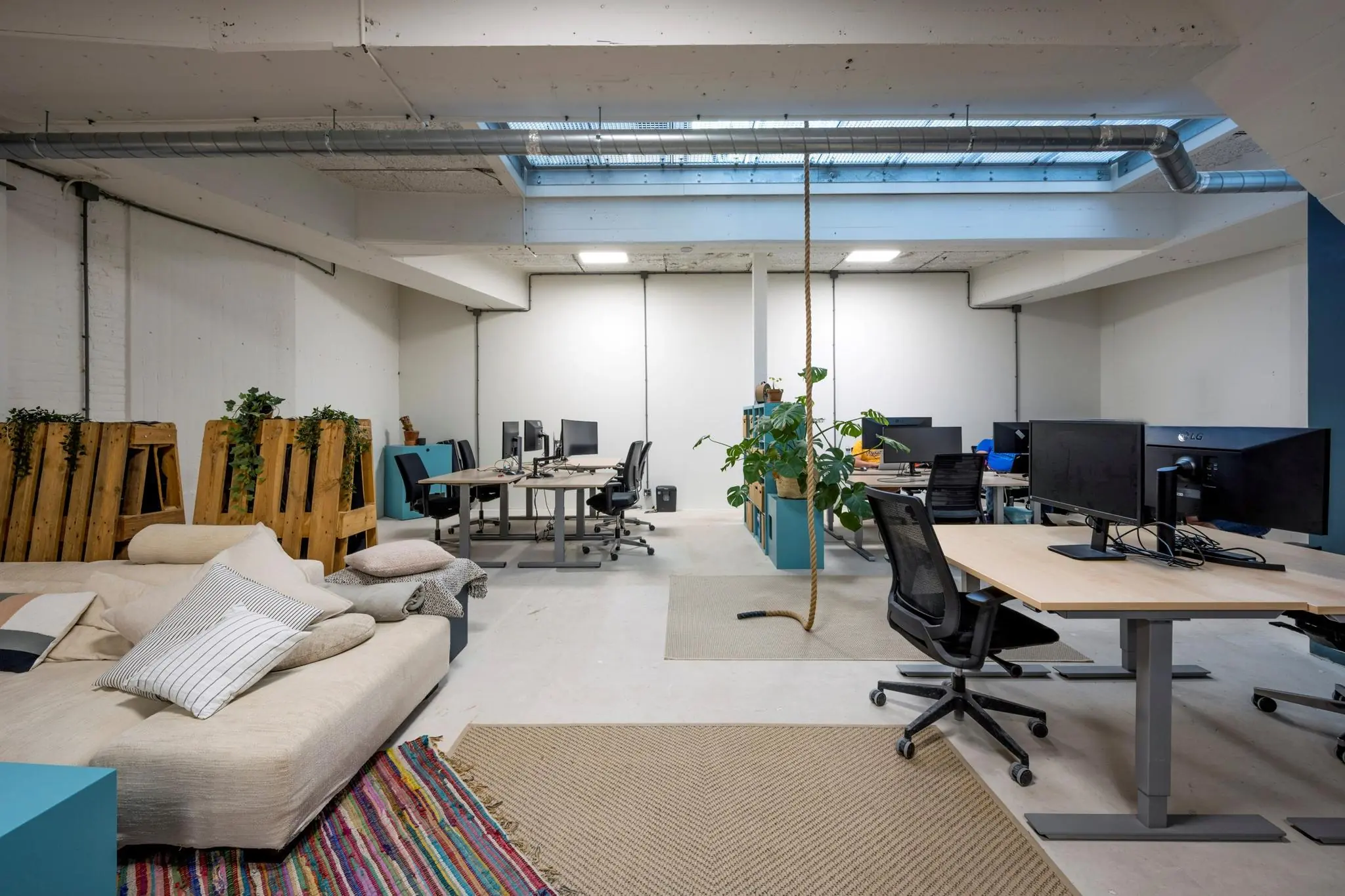 Modern kantoorinterieur aan de James Wattstraat met werkplekken, loungehoek en natuurlijk licht via een dakraam.